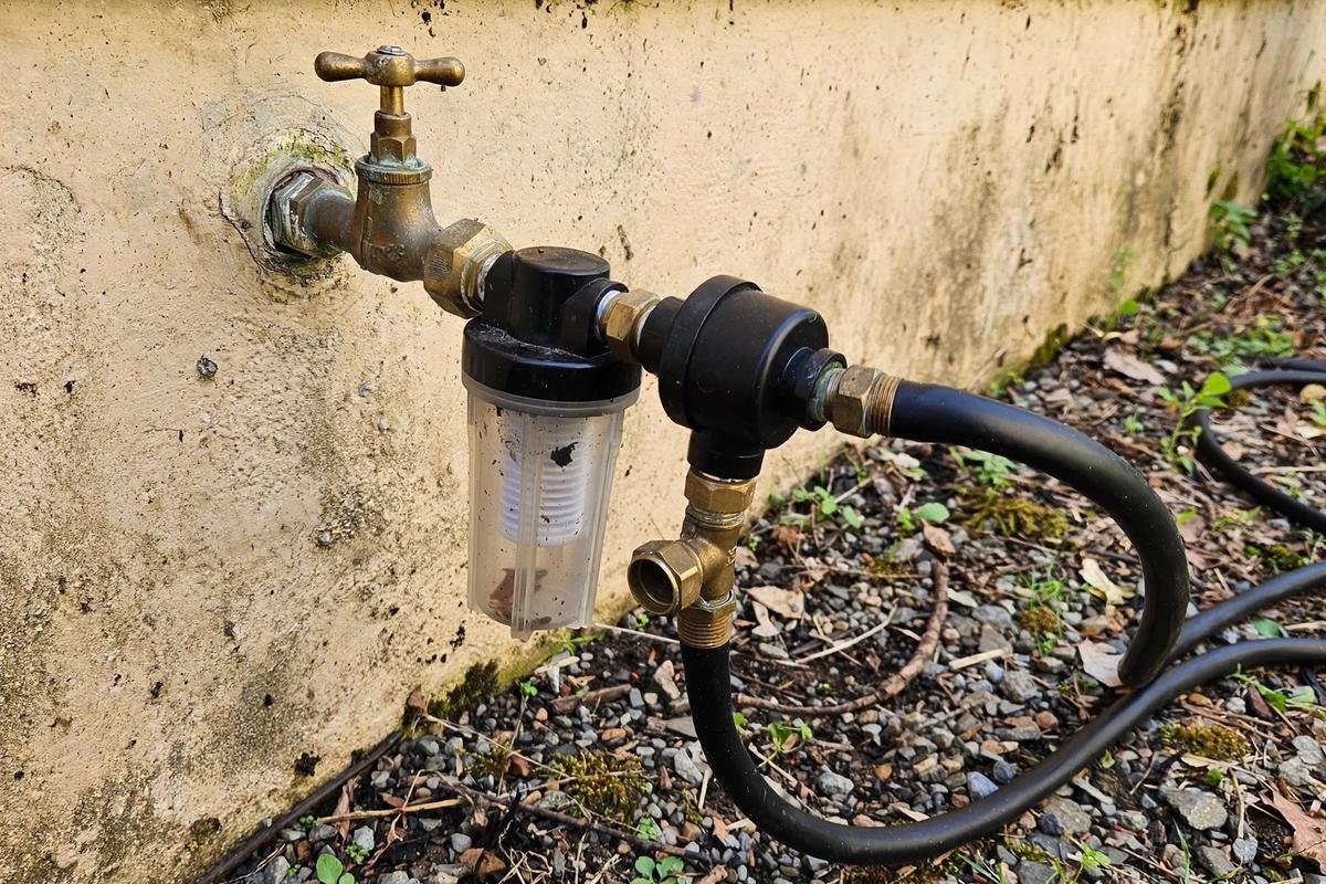 Pressure regulator and filter assembly connected at an outdoor faucet feeding a black mainline tube